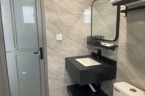 Een moderne badkamer met een douchedeur van glas, een zwarte wastafel en een wit toilet.