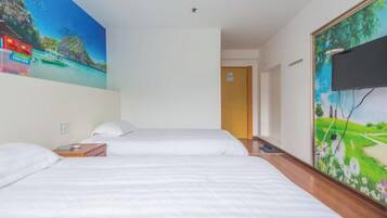 Une chambre d’hôtel avec deux lits, un tableau représentant une plage tropicale et un téléviseur fixé au mur.