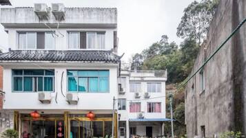A traditional building with a tiled roof, a storefront with glass doors, and a visible balcony.