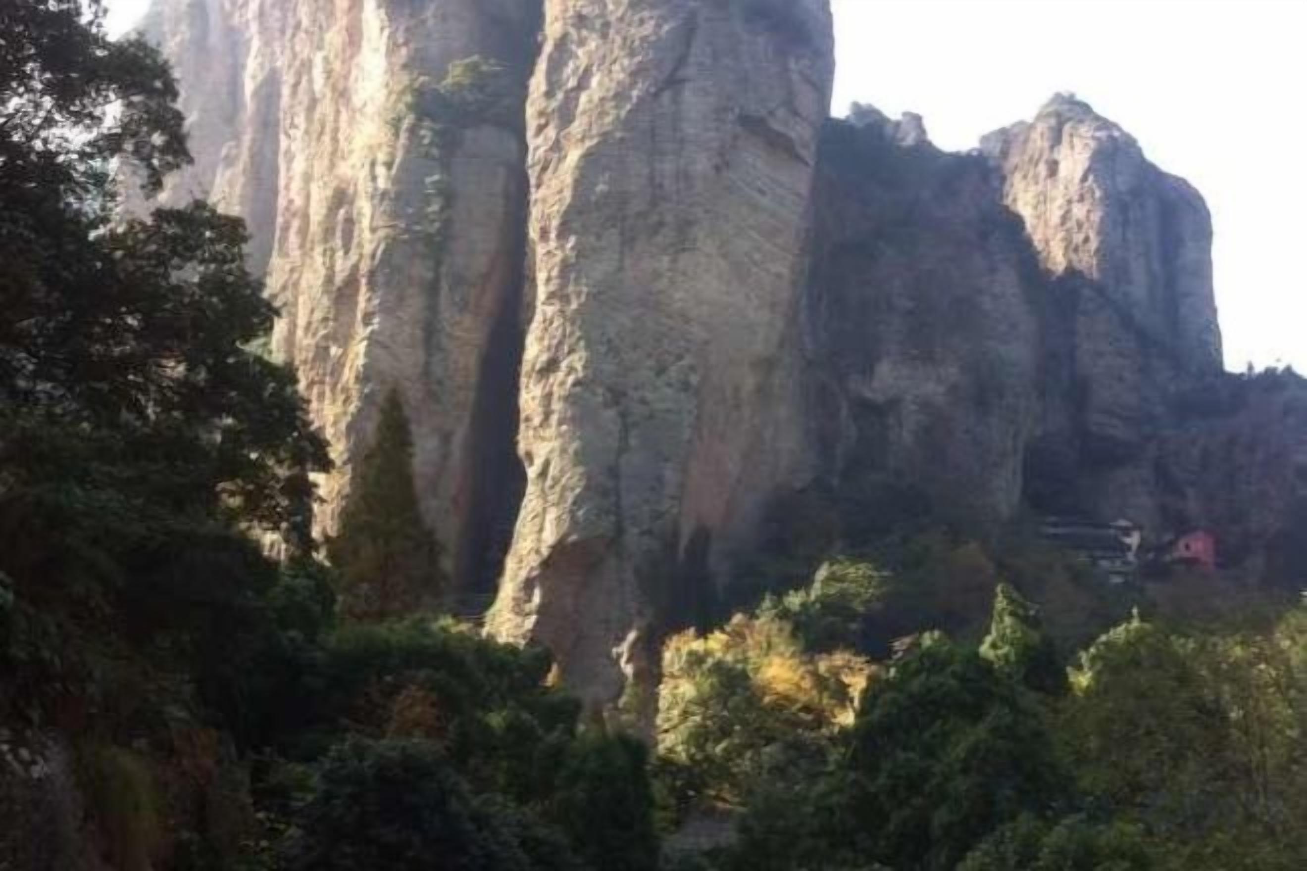 Une formation rocheuse naturelle, avec une zone boisée au premier plan.