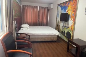 A hotel room with a bed, a chair, a small table, a TV mounted on the wall, and a painting of a bridge. - Yandang Mountain Xiufeng Tower (Yueqing)