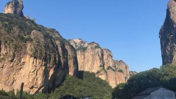 A mountain landscape with a prominent rock formation and a small building in the foreground.