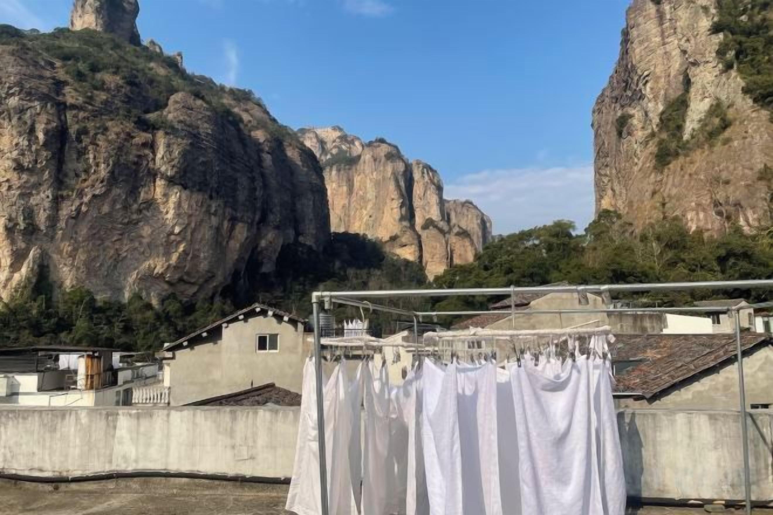 A rooftop with a clothesline, buildings, and a rocky mountain backdrop.
