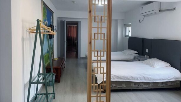 A hotel room with a bed, a wooden screen, a painting, and a clothes rack. - Yandang Mountain Xiufeng Tower (Yueqing)