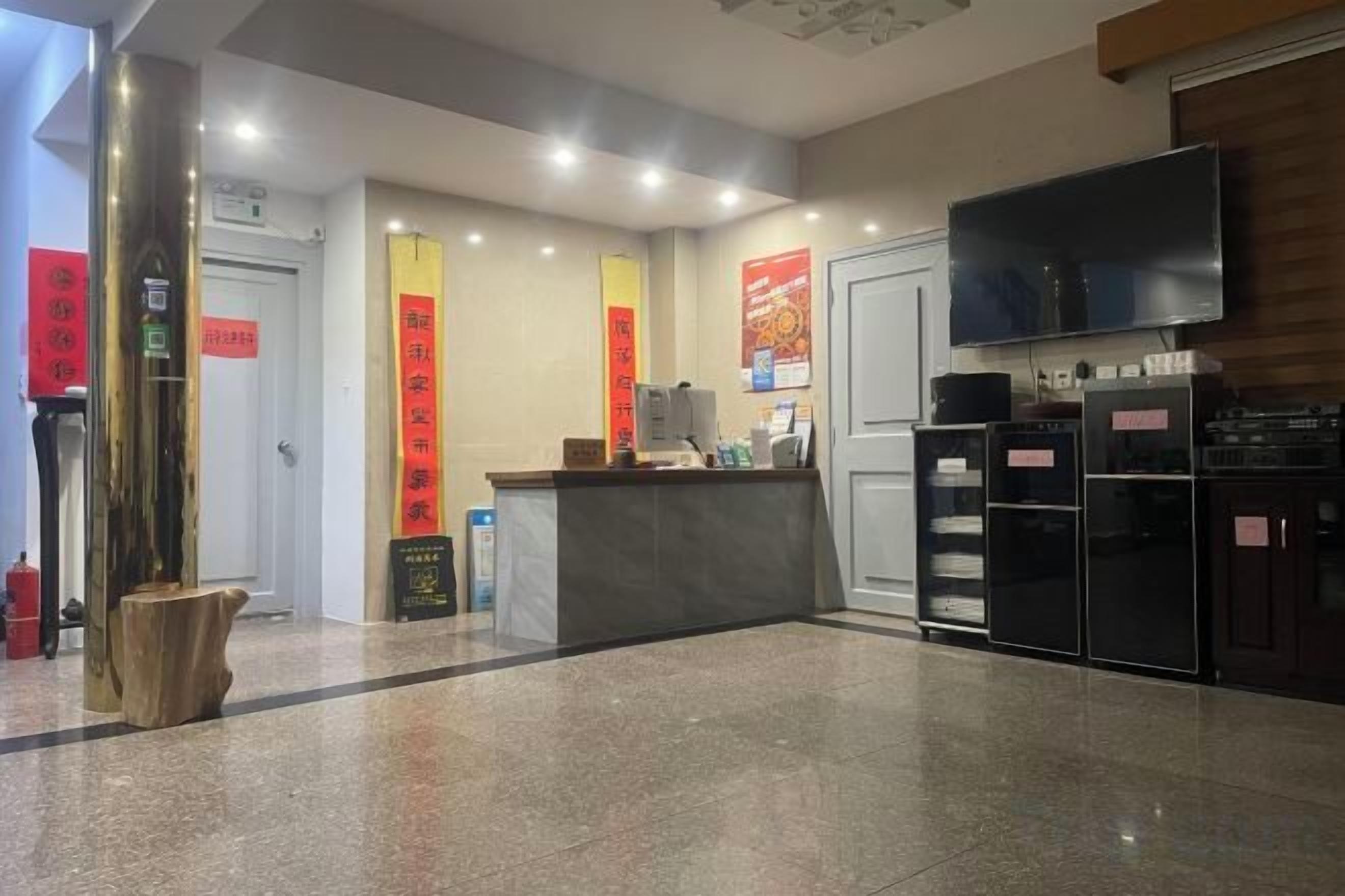 A reception area with a counter, a flat-screen TV, and a refrigerator.