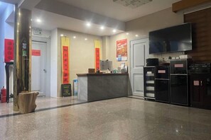 Una zona d'entrada amb mostrador, televisió de pantalla plana i nevera.