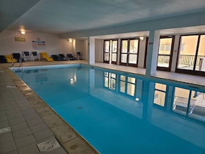 En swimmingpool med liggestole, en livredderskrank og udsigt ud