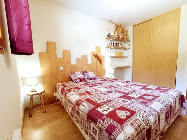 Une chambre à coucher avec une tête de lit en bois, une couvre-lit matelassée, une petite table de chevet avec une lampe et une armoire.