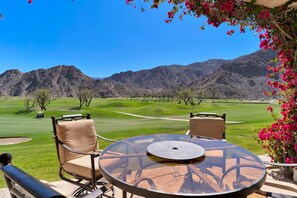 A table and chairs with a view of a golf course and mountains.