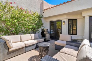 An outdoor patio with a sofa set, a grill, and a table. - Desert Greens Villa | 3BR Santa Rosa Cove (La Quinta)