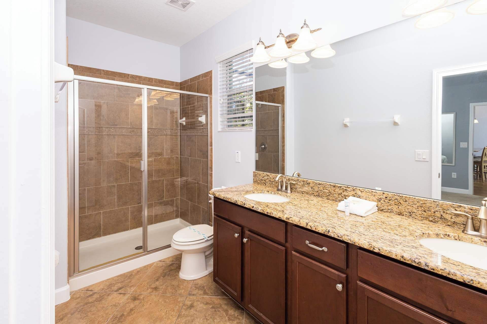 A modern bathroom with a glass-enclosed shower, a vanity with a sink and mirror, and a toilet.