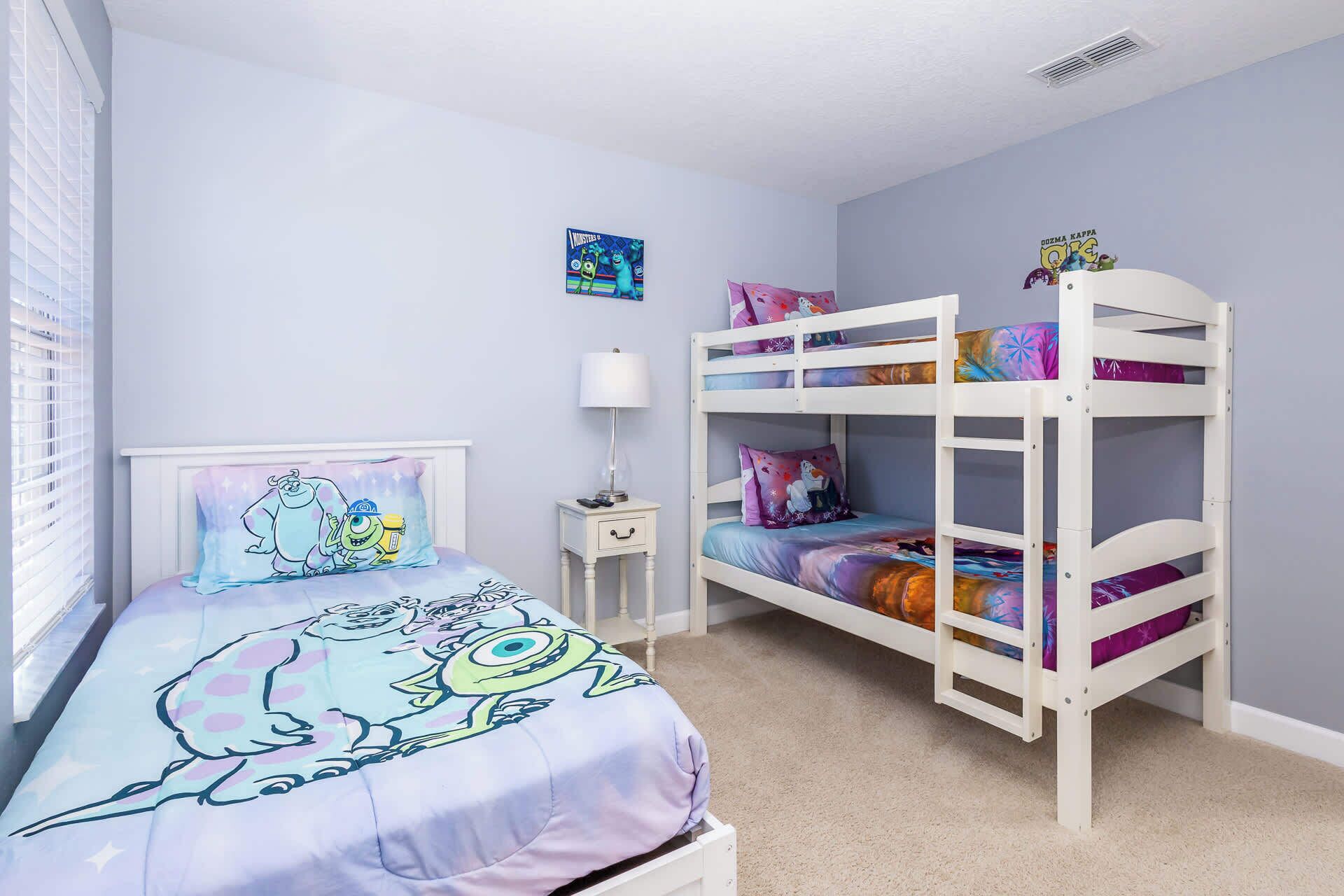 A child's bedroom with bunk beds, a bedside table, a lamp, and a wall decoration.