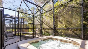 Un área con jacuzzi cubierto de vidrio, con sillas y piscina.