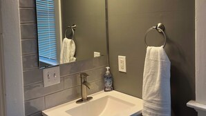 A bathroom with a white sink, a mirror, and three wall-mounted lights.
