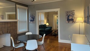 A dining area with a round table and chairs, a ceiling fan, and artwork on the walls.