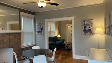 A dining area with a round table and chairs, a ceiling fan, and artwork on the walls.