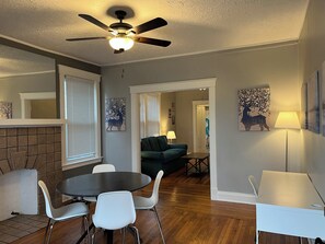 A dining area with a round table and chairs, a ceiling fan, and artwork on the walls. - Rolston 1, One Bedroom Unit near Xavier, Downtown (Cincinnati)