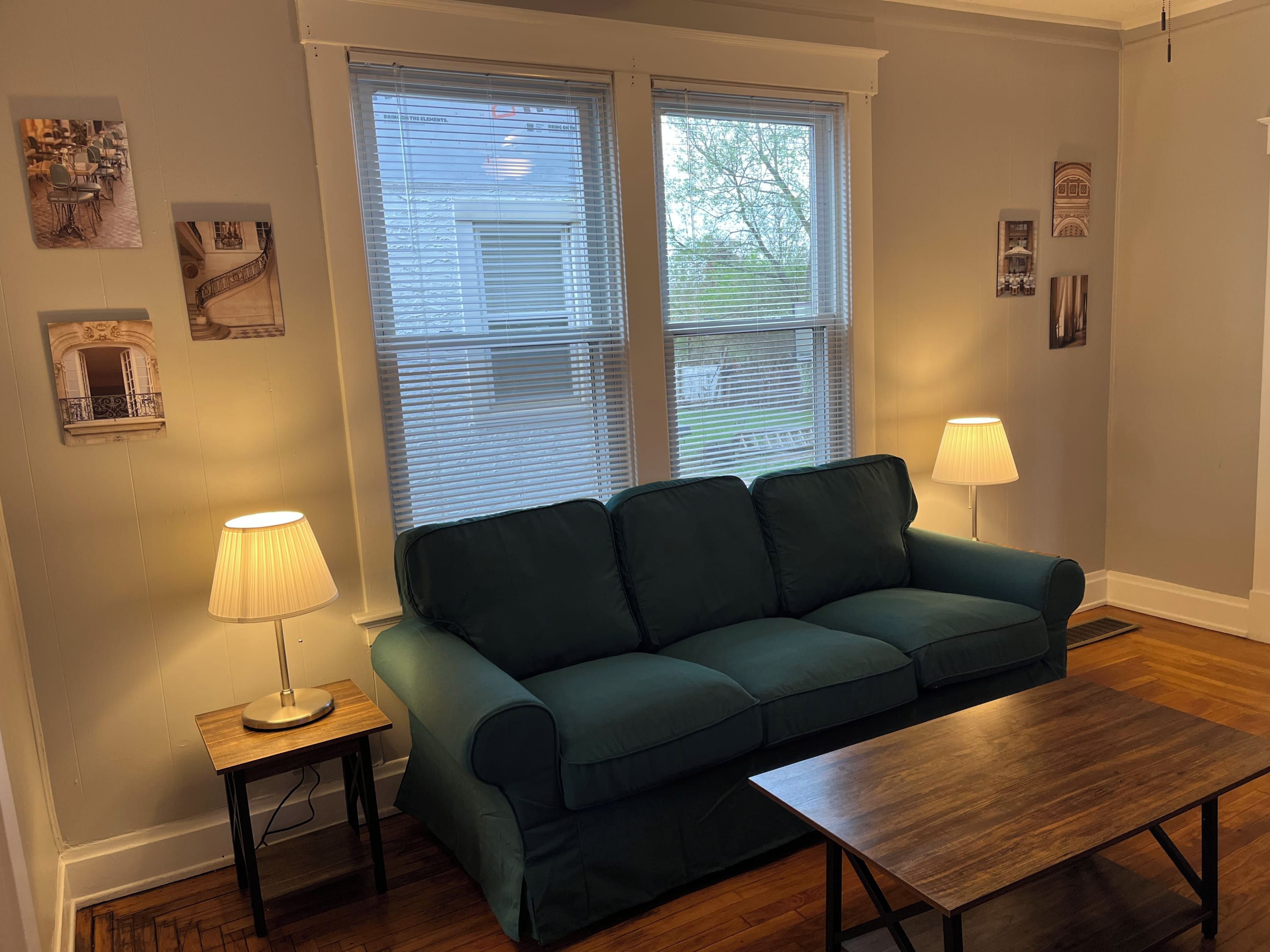 A living room with a green sofa, a wooden coffee table, and two lamps.