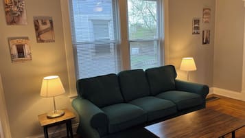 Una sala de estar con un sofá verde, una mesa de centro de madera y dos lámparas.