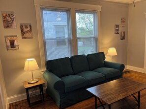 Een woonkamer met een groene bank, een houten salontafel en twee lampen.