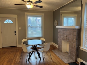 A dining area with a round table and four chairs, a ceiling fan, and a fireplace with a tiled surround.
