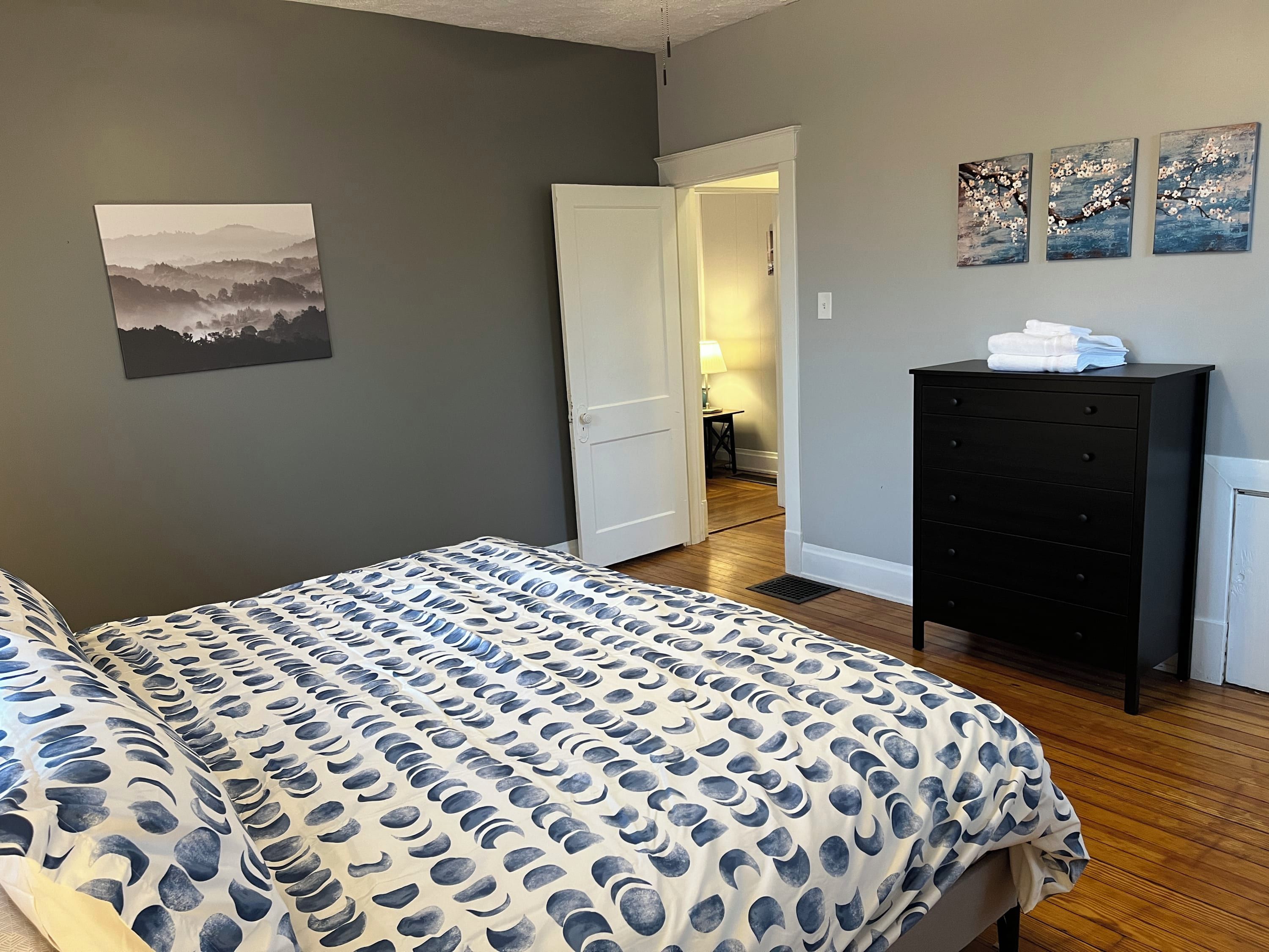Une chambre à coucher comprenant un lit, une commode et une porte donnant sur une autre pièce.