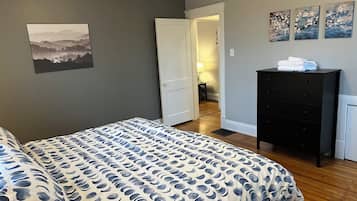 Une chambre à coucher comprenant un lit, une commode et une porte donnant sur une autre pièce.