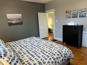 Een slaapkamer met een bed, een dressoir en een deur naar een andere kamer.