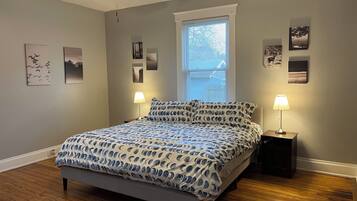 A bedroom with a bed, two bedside lamps, a ceiling fan, and a window with blinds.