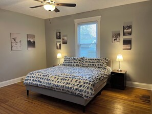 A bedroom with a bed, two bedside lamps, a ceiling fan, and a window with blinds. - Rolston 1, One Bedroom Unit near Xavier, Downtown (Cincinnati)