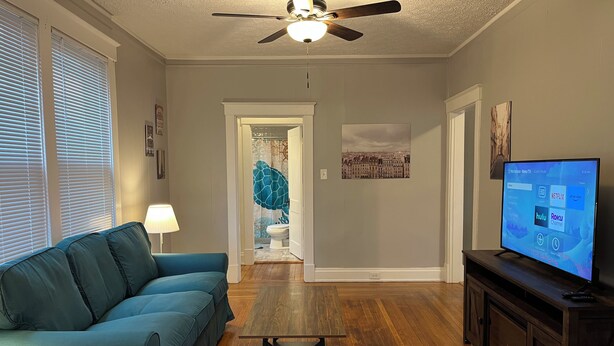 A living room with a sofa, a coffee table, a fireplace, and a television displaying a streaming service interface.