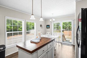 Una cocina con encimera de madera, armarios blancos y luces colgantes.