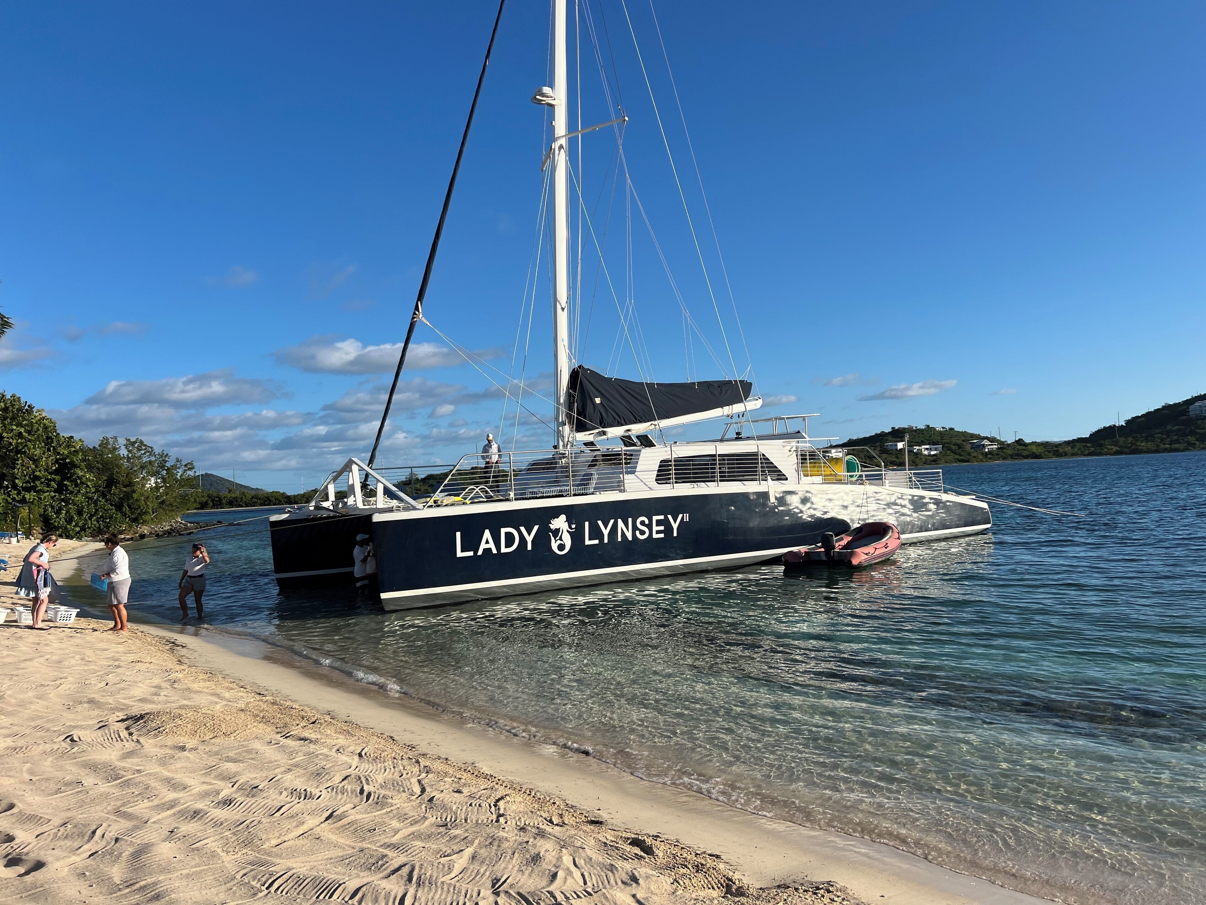 Eine Yacht namens "Lady Lynsey" liegt an einem Strand mit klarem Wasser und Sandstrand.