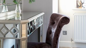 A room with a mirror, a vase with flowers, a chair, and two framed pictures on the wall. - Penthouse apartment on Cromwell road (London)