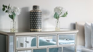 A mirrored bedside table with a decorative vase and a bottle on top. - Penthouse apartment on Cromwell road (London)
