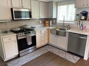 A modern kitchen with white cabinets, a stainless steel stove, a microwave, and a dishwasher.