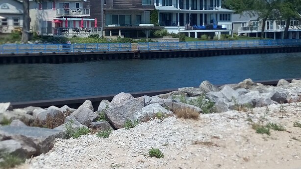 Une propriété située au bord de l’eau, comprenant un bâtiment moderne à deux étages, un quai et une côte rocheuse.