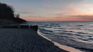 Une plage bordée d’une côte rocheuse et dotée d’une jetée qui s’avance dans l’eau.