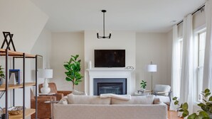 A living room with a fireplace, a sofa, a television, and a bookshelf.