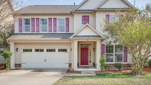 A two-story house with a garage, a red front door, and a small porch.