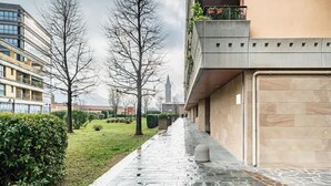 Un chemin bordé d’arbres et un bâtiment dont la façade est recouverte de tuiles.