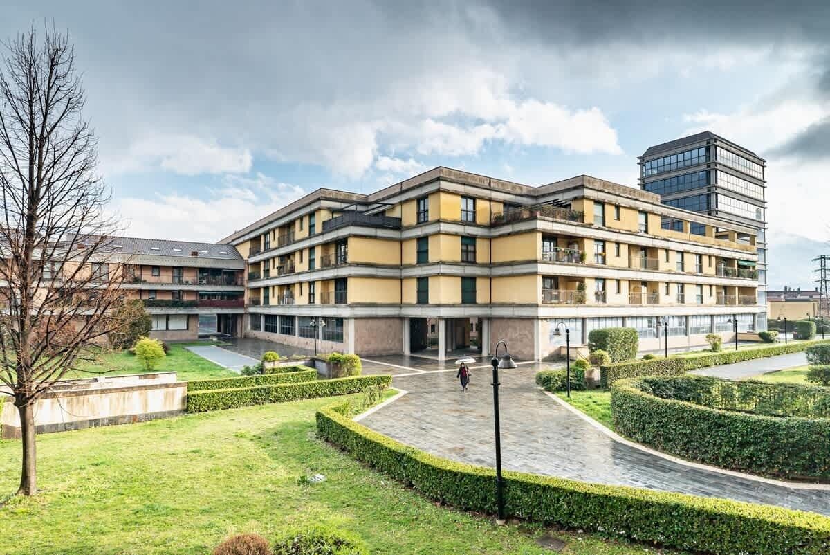 Un hôtel à plusieurs étages doté d’une cour intérieure, entourée de haies bien taillées et d’un petit arbre.