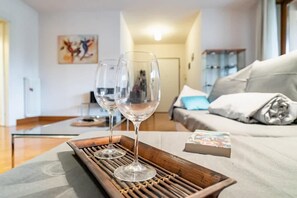 Un salon moderne avec un canapé, une table basse et deux verres à vin posés sur un plateau.