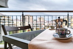 Un balcon avec une table, une chaise, une cafetière et une tasse.