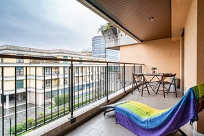 Un balcon avec un hamac, une table et des chaises.