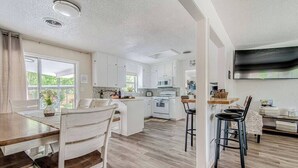 A spacious kitchen with white cabinets, a central island, and a dining area with a wooden table and chairs. - Taste of Tuscany - Hot Tub, Fire Pit & Pool Table (Fredericksburg)