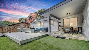 A backyard with a patio, outdoor furniture, and a large umbrella. - Taste of Tuscany - Hot Tub, Fire Pit & Pool Table (Fredericksburg)
