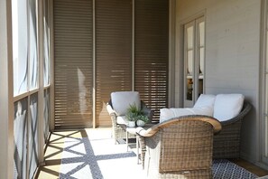 A sunlit balcony with wicker furniture, a potted plant, and a patterned floor. - The Sadie, Walk to Campus, by Velvet Ditch Villas (Oxford)
