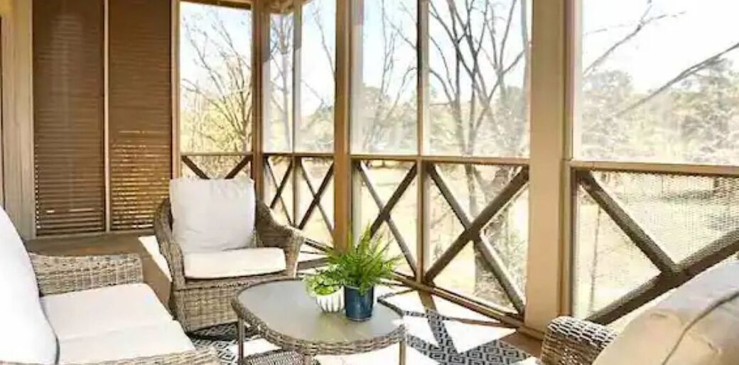 A covered outdoor seating area with wicker furniture and a small table with a plant.