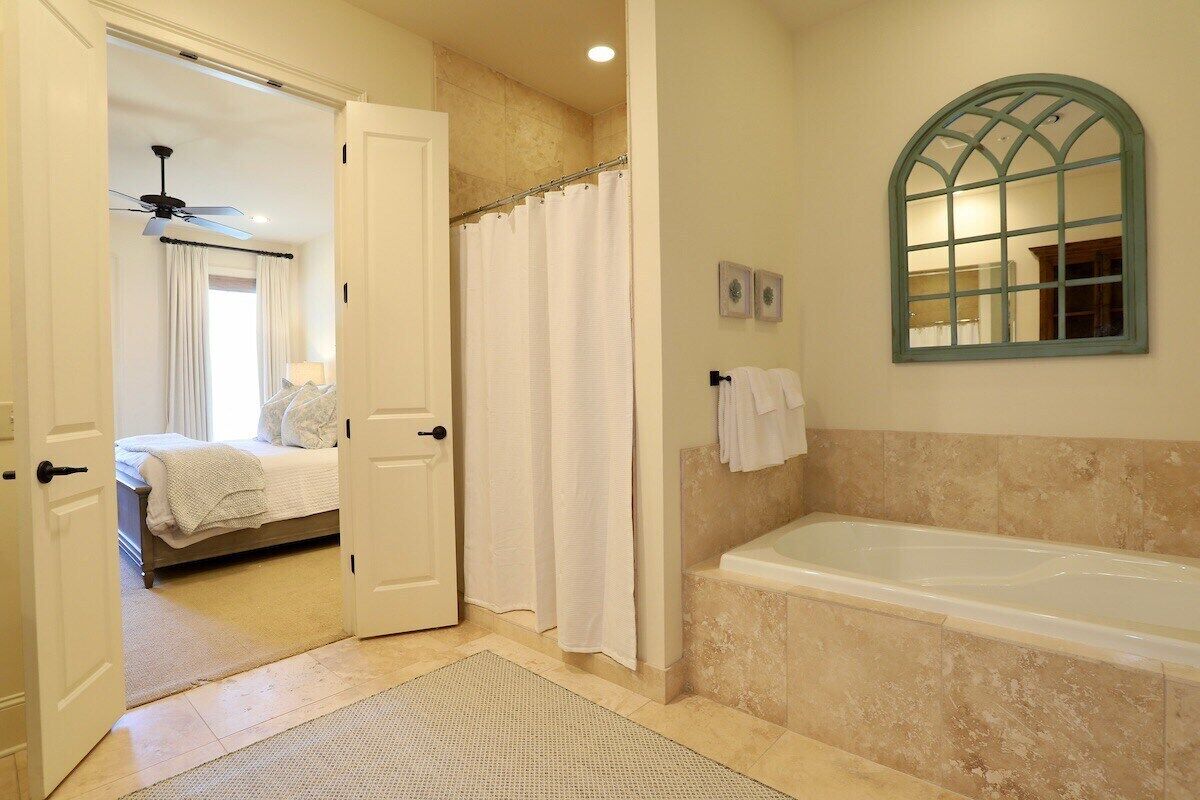 A bathroom with a bathtub, a shower curtain, and a mirror.